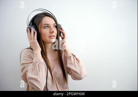 Das Millennials-Hipster-Mädchen liebt Musik-Podcasts in Kopfhörern, zeigt mit dem Finger auf den Werbespot für Ihre Werbung, hat überraschend fröhlichen Ausdruck, isoliert auf lila Hintergrund Stockfoto