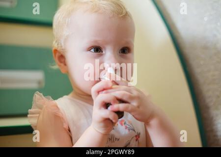 Little Girl mit einem Spray oder Nasentropfen zur Behandlung einer laufenden Nase bei einer Erkrankung zu Hause im echten Leben. Stockfoto