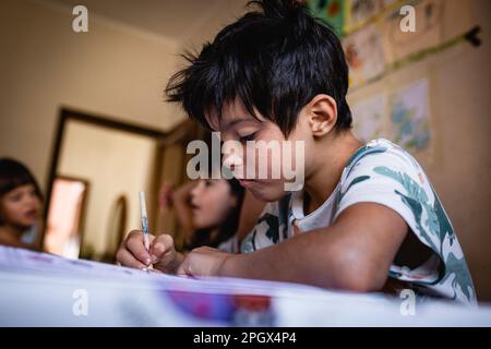 Kinder, die zu Hause am Küchentisch sitzen und Hausaufgaben machen Stockfoto