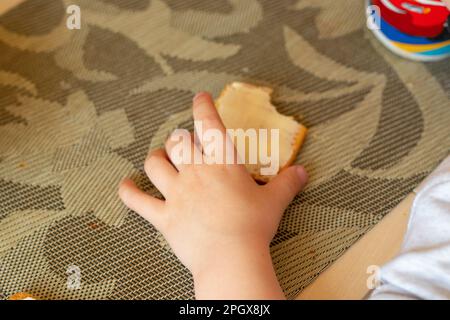 Kinderhände und Kekse mit Butter auf dem Tisch Stockfoto