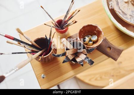 Draufsicht von Bürsten und anderen Keramikwerkzeugen auf dem Holztisch Stockfoto