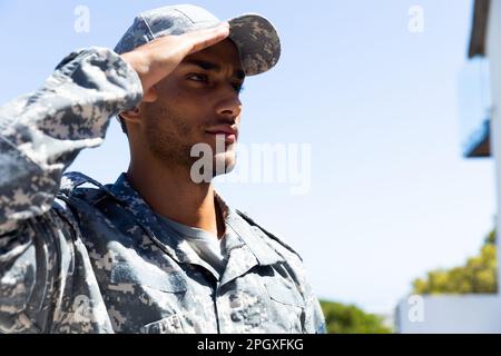 Ein birassischer Soldat, der Militäruniform trägt, draußen salutiert, mit Kopierraum Stockfoto