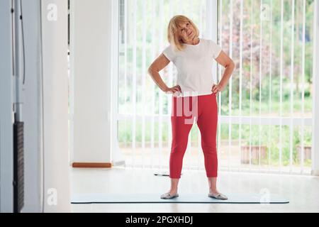 Positive Seniorin in Sportkleidung im Innenbereich tagsüber beim Training Stockfoto