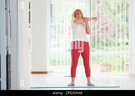 Positive Seniorin in Sportkleidung im Innenbereich tagsüber beim Training Stockfoto