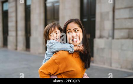 Glückliche südostasiatische Mutter mit ihrer Tochter, die Spaß im Stadtzentrum hat - nette Familie draußen Stockfoto