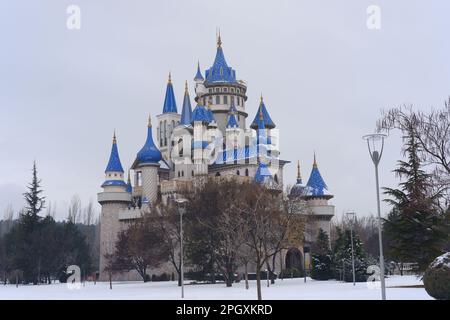 Nostalgische alte Burg im Sazova Park Eskisehir mit blauen Türmen. Unter Schnee an einem kalten Wintertag mit Bäumen und Büschen unter Schnee. Stockfoto