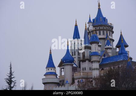 Nostalgische alte Burg im Sazova Park Eskisehir mit blauen Türmen. Unter Schnee an einem kalten Wintertag mit Bäumen und Büschen unter Schnee. Stockfoto