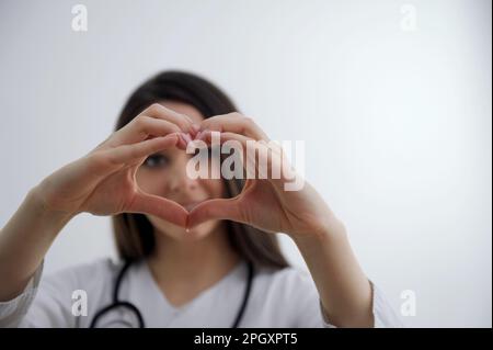 Nahaufnahme zweier weißer weiblicher Hände isoliert auf weißem Hintergrund. Junge Frau, die mit ihren Fingern eine Herzform bildet. Horizontale Farbfotografie. Blickwinkel-Aufnahme. Hochwertiges Foto Stockfoto