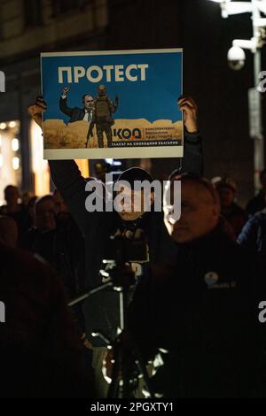 Ein Protestteilnehmer steht mit einem Poster auf dem Treffen gegen Präsident Radev in Sofia in der Nacht Stockfoto