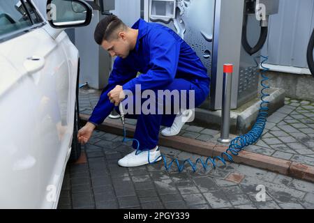 Professioneller Mechaniker, der Reifen beim Autoservice aufpumpt Stockfoto