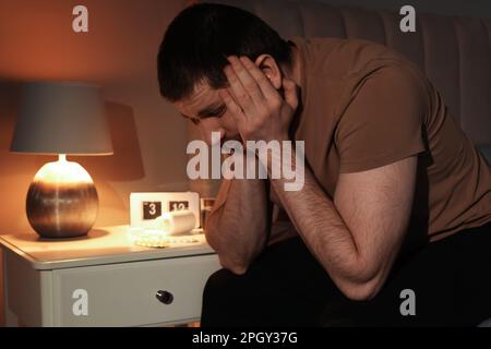 Mann leidet nachts an Schlafstörungen im Schlafzimmer Stockfoto