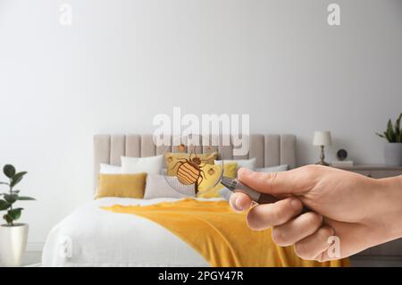 Frau mit Lupe, die Bettwanzen im Schlafzimmer erkennt, schließt Stockfoto