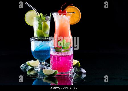 Eine Gruppe Cocktails auf reflektierendem Glas vor schwarzem Hintergrund. Stockfoto