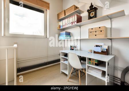 Ein Home-Office-Bereich mit weißen Wänden und Holzregalen an der Wand ist mit verschiedenen Arten von Lagerboxen gefüllt Stockfoto