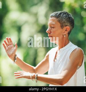 Frau, die Qigong im Wald praktiziert Stockfoto