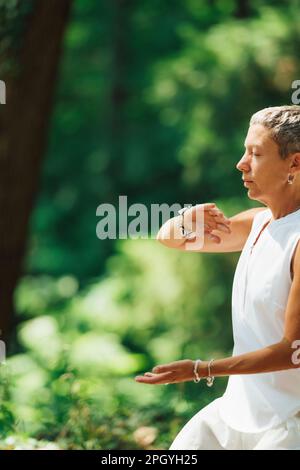 Frau, die Qigong im Wald praktiziert Stockfoto