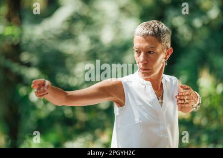 Frau, die Qigong im Wald praktiziert Stockfoto