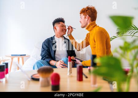 Wunderschönes schwules Paar, das sich schminkt und Spaß hat, zu Hause romantisch zu sein, lgbt-Konzept Stockfoto