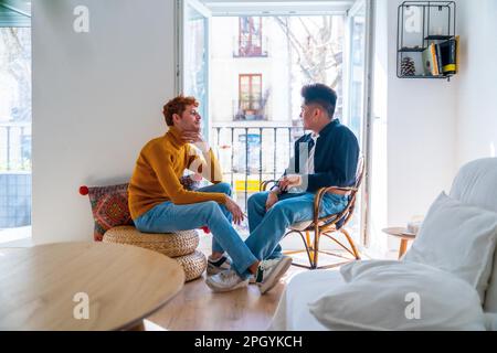 Wunderschönes schwules Paar, das zu Hause romantisch ist, mit dem Balkon von zu Hause reden, lgbt-Konzept Stockfoto