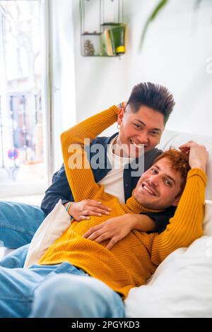 Wunderschönes schwules Paar, das zu Hause auf dem Sofa romantisch ist, mit Porträt kuscheln, lgbt-Konzept Stockfoto