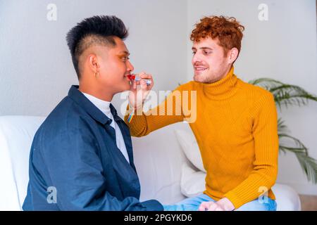 Wunderschönes schwules Paar, das sich schminkt, seine Lippen malt, zu Hause romantisch zu sein, lgbt-Konzept Stockfoto