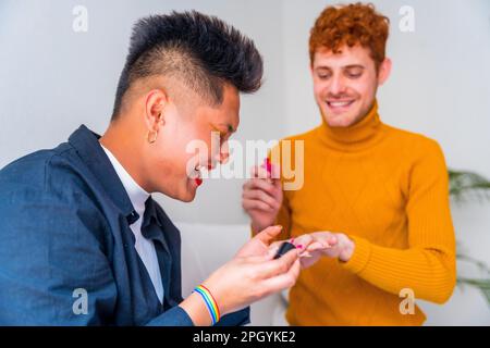 Wunderschönes schwules Paar, das sich schminkt, seine Nägel lackiert und zu Hause drinnen Spaß hat, lgbt Concept Stockfoto