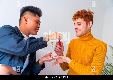 Wunderschönes schwules Paar, das sich schminkt, seine Nägel lackiert und zu Hause drinnen Spaß hat, lgbt Concept Stockfoto