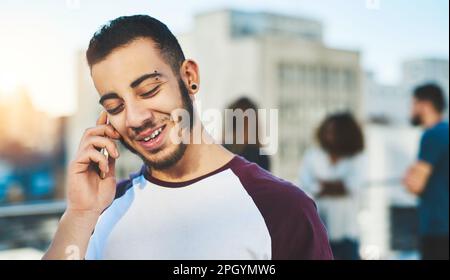 Hey, wie geht's? Ein gutaussehender junger Mann, der telefoniert, während er draußen steht. Stockfoto