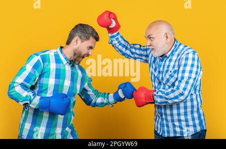 Wütende Männer der 2. Generation, die isoliert auf Gelb kämpfen. Generationsmänner kämpfen im Studio. Stockfoto