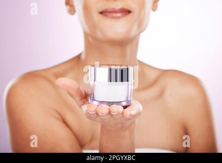 Hände, Cremebecher und Hautpflege einer Frau im Studio isoliert auf lila Hintergrund. Gesichts-, Dermatologie- und Frauenmodell-Lotion Stockfoto