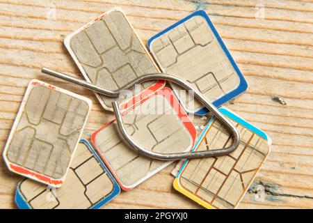 sim-Karten und ein Stift zum Öffnen des Einsatzes für eine sim-Karte liegen auf einem Holztisch Stockfoto