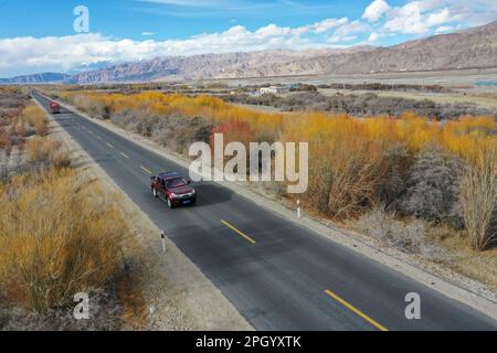(230325) -- TAXKORGAN, 25. März 2023 (Xinhua) -- Dieses areiale Foto wurde am 19. März 2023 aufgenommen und zeigt Nurkerim Duri, die nach der Wiederauffüllung der Lagerbestände im Autonomen Bezirk Taxkorgan Tajik, Nordwestchina, der Autonomen Region Xinjiang Uygur, zurück nach Aimin fährt. Das Leben des Hirten Duri Jarman ist eng mit zwei Orten verbunden: Dem Dorf AK Toga Langar, eingebettet tief in die Berge des Taxkorgan Tajik Autonomous County, und dem Dorf Aimin, das sich in der Nähe des Bezirkssitzes befindet. Duri, jetzt 52 Jahre alt, lebte 47 Jahre im Dorf AK Toga Langar. Im Winter 2018 profitierte seine Familie davon Stockfoto