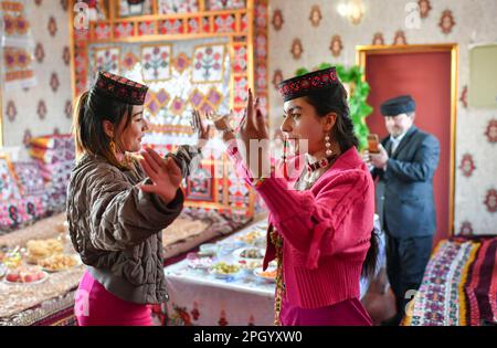 (230325) -- TAXKORGAN, 25. März 2023 (Xinhua) -- Gvzalnur (R, Front), Nichte von Duri Jarman, tanzt mit ihrem Freund in Duris Haus in Aimin, Dorf Taxkorgan Tajik Autonomous County, Nordwestchina's Autonome Region Xinjiang Uygur, 21. März 2023. Das Leben des Hirten Duri Jarman ist eng mit zwei Orten verbunden: Dem Dorf AK Toga Langar, eingebettet tief in die Berge des Taxkorgan Tajik Autonomous County, und dem Dorf Aimin, das sich in der Nähe des Bezirkssitzes befindet. Duri, jetzt 52 Jahre alt, lebte 47 Jahre im Dorf AK Toga Langar. Im Winter 2018 profitierte seine Familie von der Umsiedlung Stockfoto