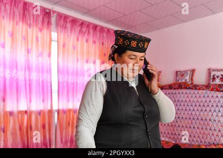 (230325) -- TAXKORGAN, 25. März 2023 (Xinhua) -- Nanik Kukan ruft ihren Busband Duri Jarman in Aimin, Dorf Taxkorgan Tajik Autonomous County, Nordwestchina, Autonome Region Xinjiang Uygur, am 25. November 2019 an. Vor dem Umzug musste sie zur Regierung gehen, wenn sie ihre Verwandten anrufen wollte. Das Leben des Hirten Duri Jarman ist eng mit zwei Orten verbunden: Dem Dorf AK Toga Langar, eingebettet tief in die Berge des Taxkorgan Tajik Autonomous County, und dem Dorf Aimin, das sich in der Nähe des Bezirkssitzes befindet. Duri, jetzt 52 Jahre alt, verbrachte 47 Jahre in AK To Stockfoto