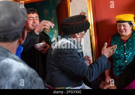 (230325) -- TAXKORGAN, 25. März 2023 (Xinhua) -- Nurkerim Duri, jüngster Sohn von Duri Jarman, bringt Mehl auf den Schultern der Visiere als traditionelles Mittel des Segens im Dorf Aimin im Autonomen Bezirk Taxkorgan Tajik, Nordwestchina's Autonome Region Xinjiang Uygur, 21. März 2023. Das Leben des Hirten Duri Jarman ist eng mit zwei Orten verbunden: Dem Dorf AK Toga Langar, eingebettet tief in die Berge des Taxkorgan Tajik Autonomous County, und dem Dorf Aimin, das sich in der Nähe des Bezirkssitzes befindet. Duri, jetzt 52 Jahre alt, lebte 47 Jahre im Dorf AK Toga Langar. Im Winter 2018 Stockfoto