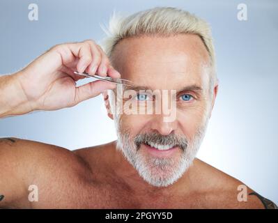 Seniorenmann, Pinzette und Augenbraue im Porträt mit Lächeln, Schönheit und Pflege im Studiohintergrund. Happy Model, Pinzette und Haarentfernung für die Reinigung Stockfoto
