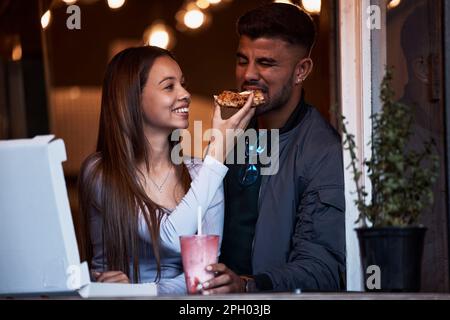 Pizza, Restaurant und Happy Pair füttern Fast Food zu einem verspielten romantischen Date zum Valentinstag, um sich zu verbinden und eine schöne Zeit zusammen zu verbringen. Hunger, Liebe und Stockfoto