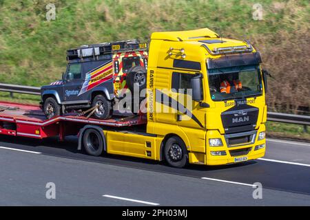 BARRS TRANSPORT LTD 2013 (63 PS) Schild MAN Diesel 18,440 4x2 BLS XM Zugmaschine mit SIGNATURE Wide-Load Escort 2011 LAND ROVER Defender Hard Top 2402cc 6-Gang-Schaltgetriebe auf Tieflader mit Stufenanhänger. Eine Rückladung nach der Auslieferung; Fahrt auf der Autobahn M6 UK Stockfoto