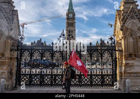 Ottawa, Kanada. 24. März 2023. Ein Demonstrant hält eine rote Flagge mit einem Ahornblatt als US-amerikanischer Präsident Joe Biden besucht die Hauptstadt Canadaís vor dem Parlamentshügel in Ottawa. Dies ist der erste offizielle Besuch des amerikanischen Präsidenten in Kanada seit seiner Präsidentschaftswahl. Obwohl Besuche zwischen gewählten Präsidenten und dem alliierten Land typischerweise früher stattfinden, verzögerte sich Bidens Eröffnungsbesuch im nördlichen Nachbarn aufgrund von COVID-19-Reisebeschränkungen. Kredit: SOPA Images Limited/Alamy Live News Stockfoto