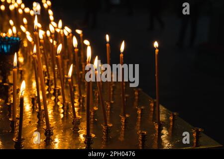 Orthodoxe Kerzen aus Bienenwachs brennen in einem dunklen Innern der Kirche Stockfoto