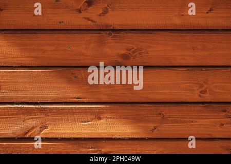 Sonnenlicht und Schatten auf einer hölzernen Wand aus farbigen Pinienbäumen, Nahaufnahme, Vorderansicht, Hintergrundstruktur Stockfoto