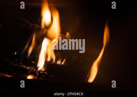 Langsam brennendes Feuer in einem Kamin in der Nacht, natürliche Nahaufnahmen mit selektivem Weichzeichner Stockfoto