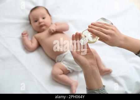 Mutter mit Massageöl in der Nähe ihres süßen Babys, Nahaufnahme Stockfoto