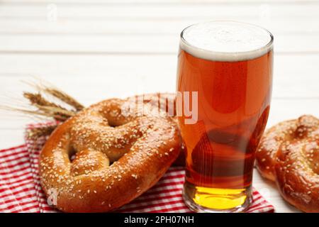 Ein Glas Lagerbier mit leckeren frisch gebackenen Brezeln auf einem weißen Tisch, Nahaufnahme Stockfoto
