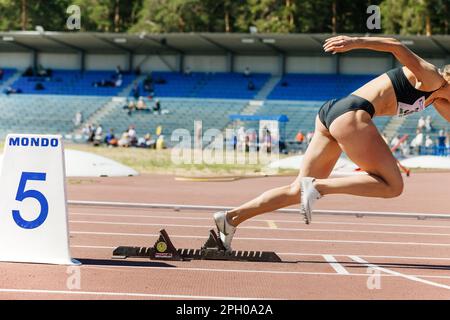 Weibliche Sprinter, die von Startblöcken in Leichtathletik, Nike Spikes Schuhen und Mondo Spurmarkierungen, sportliches Editorial Foto Stockfoto