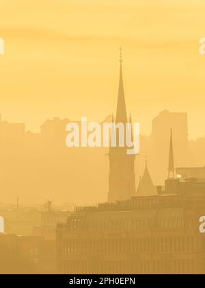 Der neblige Morgenhimmel enthüllt die Skyline von Gothenburgs mit weitläufigen Stadtlandschaften, Bauten und großen Kirchentürmen, die aus dem Dunst hervorgehen. Stockfoto