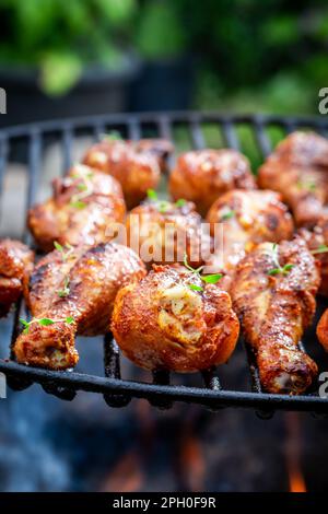 Hausgemachtes, gebratenes Hähnchenbein auf einem Grillgitter mit Feuer. Gegrilltes Hähnchen auf dem Grill mit Flammen. Stockfoto