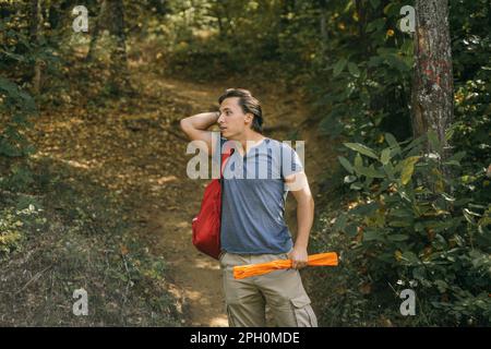 Ein gut aussehender Kerl, der in den Bergen wandert. Er wurde abgelenkt, als er seine Haare reparierte Stockfoto