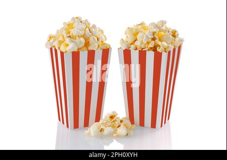 Zwei rot-weiß gestreifte Eimer mit leckerem Käsepopcorn, isoliert auf weißem Hintergrund. Schachtel mit Streuung von Popcornkörnern. Filme, Kino und Stockfoto