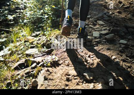 Ein Athlet der Füße tragen Sportschuhe auf einem anspruchsvollen Feldweg hautnah. Trail running Training auf felsigem Gelände im Freien. Stockfoto